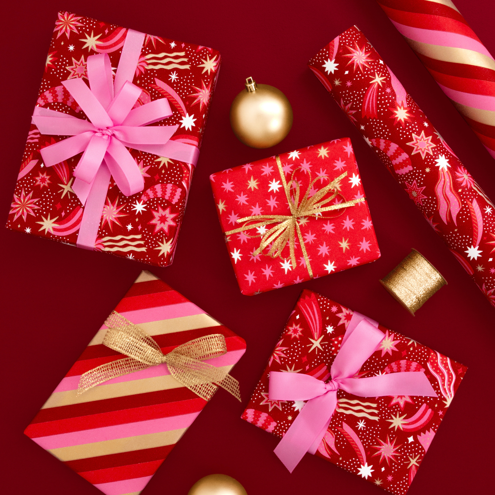 Decorative Christmas presents with ribbons and gold baubles on a red background